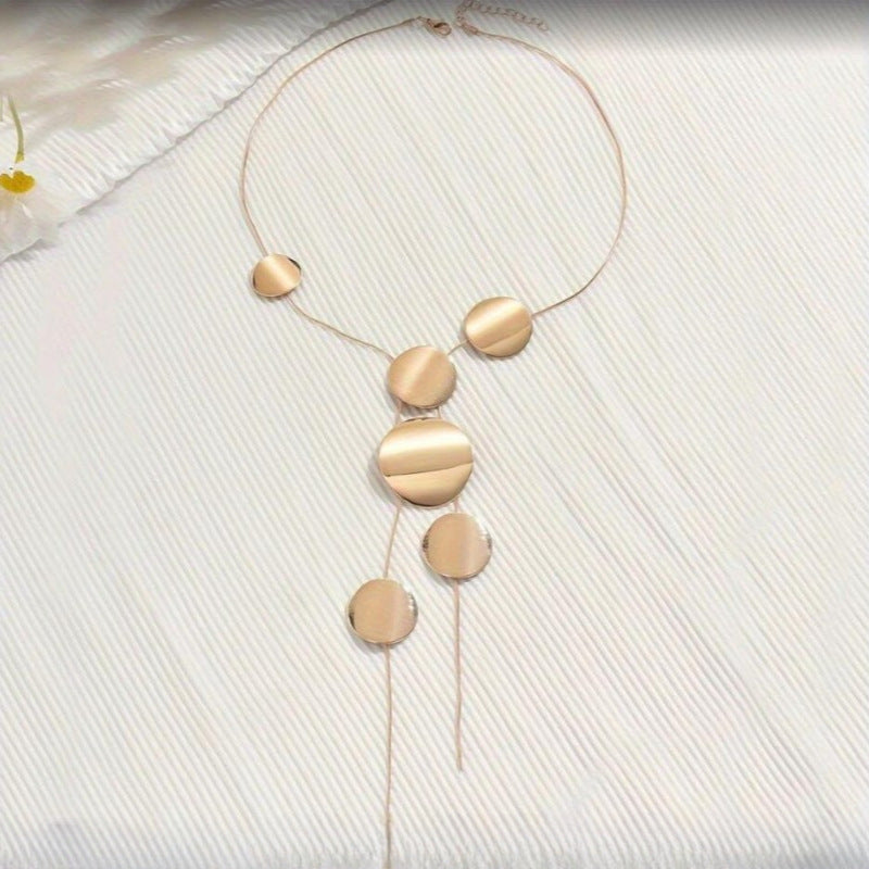 Gold necklace with round pendants on a light fabric background